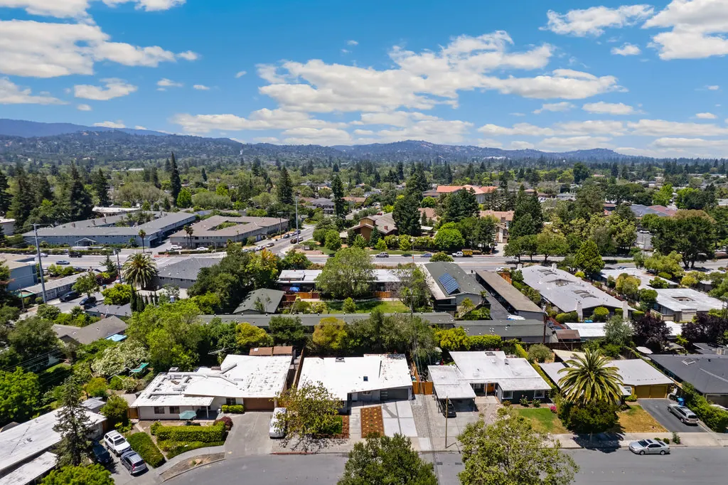 An aerial view over the Atherwood area of Redwood City, showing low single-storey rooflines beneath mature trees with the Peninsula hills behind.